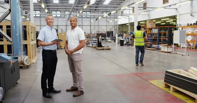 4k, Warehouse manager and a businessman using digital tablet in busy warehouse. Slow motion.