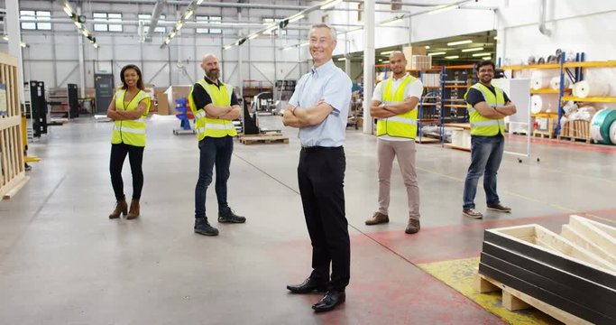 4k, Portrait of a proud mature male manager and his multi ethnic team in a warehouse. Slow motion.