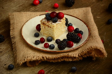 Piece of cake napoleon on a plate with sweet fresh berries