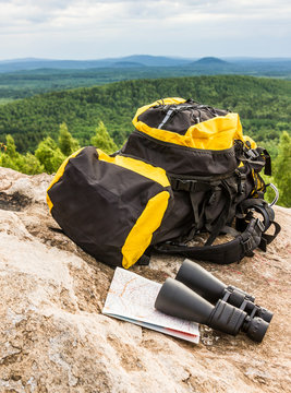 Yellow Backpack with tourist equipment binoculars map travel tourism view of background mountains and sky