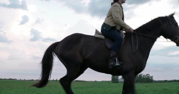 Side view of woman riding horse on field against cloudy sky