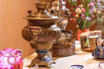 Samovar in a worn but functional condition: Russian traditional tea-drinking. Old vintage samovar on a restaurant table: kind of traditional teapot boiler.