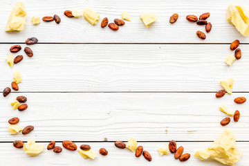 Homemade cosmetics based on cocoa butter. White wooden background top view copy space