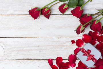 red roses/petals and gift box on old white wood table/Valentines day background