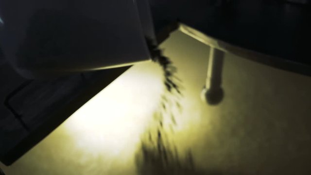 Dolly shot of brewer pouring pellet hops in beer container at brewery