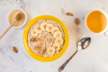 Oatmeal with banana and honey. Porridge in a yellow bowl top view