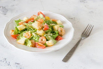 Caesar salad with shrimps on a white background