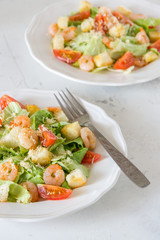 Caesar salad with shrimps on a white background