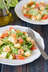 Caesar salad with shrimps on a wooden background