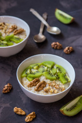 Oatmeal with kiwi fruit and walnuts. Two bowls porridge