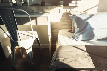 Bed maid-up with clean white  pattern pillows and bed sheets in beauty room. Close-up. Lens flair in sunlight.