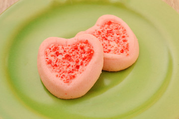 Strew berry heart cookies  on green plate 