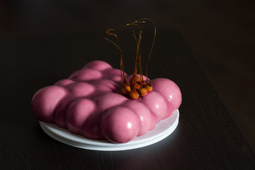 A pink cake. Nuts in caramel. Bubbles. Dark background.