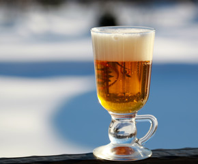 A glass with beer on a blurred natural background. Cold Beer is the best drink on a hot winter day.