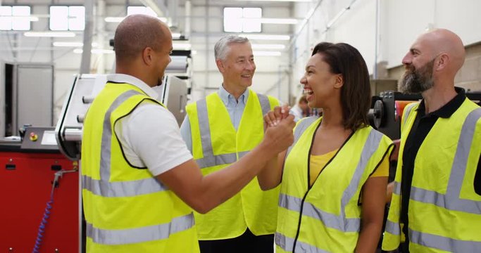 4K Happy team of workers in print factory giving high fives & smiling to camera. Slow motion.
