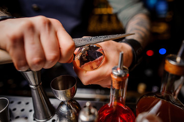 bartender cuts the ice with a special knife for cocktail preparation