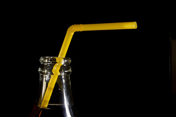 The neck of a cola bottle with a straw