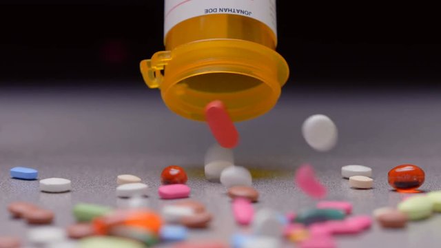 A prescription pill bottle spilling out an assortment of pills