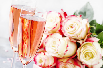 Bouquet of white and red roses, gift box, glasses with pink champagne for a pair of lovers for St. Valentines Day, gray background, selective focus