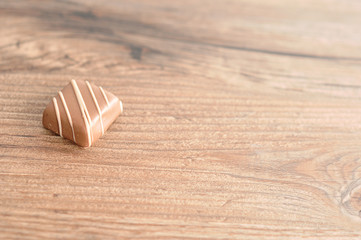 A single chocolate displayed on a wooden background