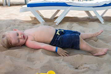 Cute kid resting on big beach in a sunny day