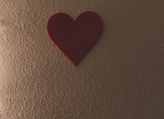 Single Red heart hanging on the wall at the top middle with dead space on the bottom