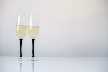 Two glasses of champagne stand on a white table