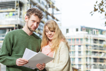 Couple on front of construction site. Real estate