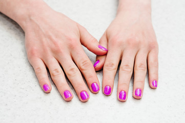 Hands on the table with manicure..Nails purple, pink.