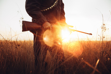Hunter holds gun at sunrise