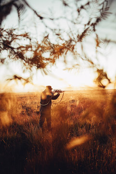 Hunter pointing with rifle on his prey in wilderness
