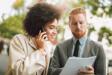 Happy business couple using smart phone outdoors