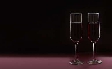 Two glasses with red wine on black backdrop. Valentine's Day concept. Copy space.