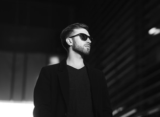 Portrait of handsome stylish man in elegant black coat. Black and white photo