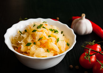 pickled cabbage and carrots in a white bowl on dark wooden background