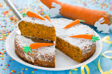 American carrot cake decorated with powdered sugar and marzipan carrot for Easter