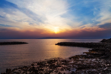Sunset on Tenerife Island with breakwaters and rocks. Canary Islands, Spain