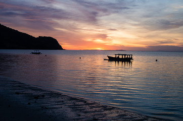 Fototapeta na wymiar Impressive sunset with traditional boat at a deserted beach near surf spot scar reef on Sumbawa, Indonesia.
