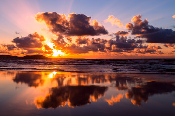 Sun and clouds reflecting in the sea water of Famara beach, Lanzarote, Canary Islands, Spain at the sunset