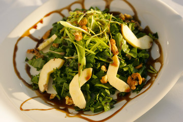 Cutted green salad with walnut and appel.