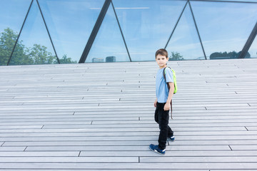 Smiling little boy with backpack outdoors