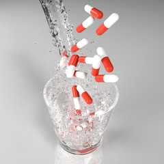 Pouring drink water into a glass with flying red and white colored medical pills capsule. Top view...