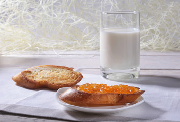 Morning Breakfast set with orange jam on bread toast and milk in glass.