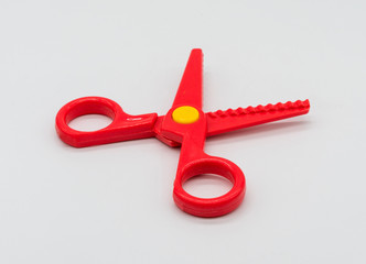 Red scissor toy with yellow dot isolated on white