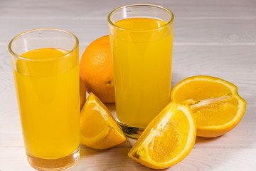 Glass of orange juice and fresh oranges on white wooden table