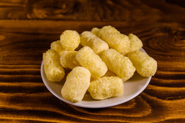 Ceramic plate with corn sticks on wooden table