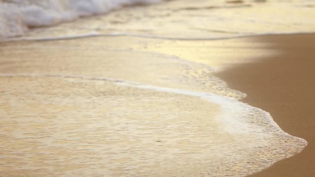 Texture of water and sand. Coast. Bright golden sand. Small waves break on the sandy shore. Sea swell