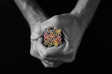 Colored pencils in hand on a black background. Creative concept. Black and white image
