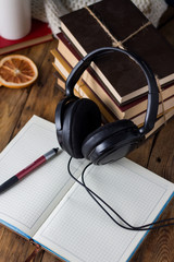 Books are stacked, Headphones, White Cup, open Diary on a wooden background. The concept of Audio Books. Taken at an angle