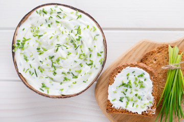 Bowl of cream cheese with green onions, dip sauce on wooden table.